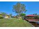 Green backyard featuring a large tree, dock, and lush landscaping at 6589 Banyan Dr, Indian Lake Estates, FL 33855