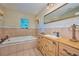 Bathroom with a vanity, large mirror, jacuzzi tub, and stained glass window at 6589 Banyan Dr, Indian Lake Estates, FL 33855