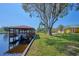 View of the dock with boat, lush landscaping, and spacious green lawn at 6589 Banyan Dr, Indian Lake Estates, FL 33855