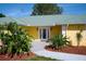 Inviting entryway with double glass doors and mature landscaping, offering a warm welcome at 6589 Banyan Dr, Indian Lake Estates, FL 33855
