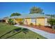 Charming yellow home with a green roof, landscaped front yard, and paved walkway at 6589 Banyan Dr, Indian Lake Estates, FL 33855