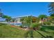 Charming yellow home featuring a carport, lush landscaping, and palm trees at 6589 Banyan Dr, Indian Lake Estates, FL 33855