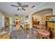 Open-concept living room with decorative ceiling fans, marble tile floors and seamless access to dining area at 6589 Banyan Dr, Indian Lake Estates, FL 33855