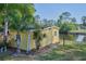 Exterior view of the yellow shed by the water with a palm tree at 6589 Banyan Dr, Indian Lake Estates, FL 33855