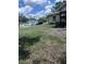 Expansive side yard featuring green grass, scattered leaves, and a glimpse of neighboring houses under a partly cloudy sky at 1211 Ne 4Th St, Mulberry, FL 33860