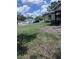 Expansive side yard featuring green grass, scattered leaves, and a glimpse of neighboring houses under a partly cloudy sky at 1211 Ne 4Th St, Mulberry, FL 33860