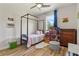 Charming bedroom with a four-poster bed, complemented by a window with blue curtains at 5008 Ne 125Th Loop, Oxford, FL 34484