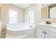 Bathroom boasts a large soaking tub, vanity with cabinet, and two windows for natural light at 4844 Creek Meadow Trl, Lakeland, FL 33810