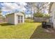 View of gray storage shed in backyard with grass, trees, and blue sky at 4844 Creek Meadow Trl, Lakeland, FL 33810