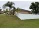 Exterior view of home featuring well-kept lawn, white fencing, and mature landscaping at 1500 Fort Meade Pl, Poinciana, FL 34759