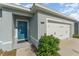 Inviting home exterior featuring a blue front door, a welcome sign, and a two-car garage at 1336 Madison Cir, Haines City, FL 33844