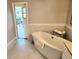 Spacious bathroom featuring a standalone tub, modern tile, and walk-out access to screened in patio at 8212 Borgia Ct, Orlando, FL 32836