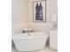 Beautiful bathtub with modern hardware, artwork, and a tile surround in a well lit modern bathroom at 8212 Borgia Ct, Orlando, FL 32836