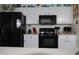 Modern kitchen features white cabinets, black appliances, and decorative display shelf at 151 Pompano Beach Dr, Kissimmee, FL 34746
