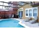 Inviting screened-in pool area with lounge chairs, dining set, barbecue, and a red patio umbrella at 151 Pompano Beach Dr, Kissimmee, FL 34746