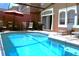 Inviting screened-in pool area with lounge chairs, dining set, barbecue, and a red patio umbrella at 151 Pompano Beach Dr, Kissimmee, FL 34746