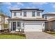 Two-story home with white siding, a two-car garage, and professionally landscaped front yard at 7744 Somersworth Dr, Kissimmee, FL 34747