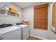 Efficient laundry room with modern washer and dryer, complemented by shelving and a window with woven shades at 1034 Foreshore Ln, Haines City, FL 33844