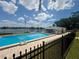 Community pool featuring a lake view, a perimeter fence, a clubhouse, and a ladder for easy access at 1550 11Th Ne St # G8, Winter Haven, FL 33881