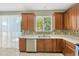 Bright kitchen area featuring wood cabinets, stainless dishwasher and sink beneath the window at 2448 Brownwood Dr, Mulberry, FL 33860