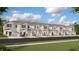 Row of townhouses with neutral colors, garages, and well-maintained landscaping on a sunny day at 3090 Chantilly Dr, Davenport, FL 33837