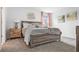 Charming bedroom featuring rustic wood bed frame, side tables, neutral palette, and large window with sunlight at 5686 Portico Pl, Kissimmee, FL 34758