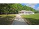 A charming single-story home has a long driveway, green grass, and mature trees at 6975 Sw 99Th St, Ocala, FL 34476