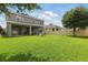 Large, green backyard with a playset, bordered by a fence and the rear of the house with a covered patio at 12243 Sawgrass Reserve Blvd, Orlando, FL 32824