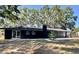 Contemporary black home boasts a spacious backyard, sliding glass doors, and a charming brick chimney at 3465 Peacock Ln, Mulberry, FL 33860