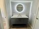 Modern bathroom features a round, lighted mirror and a gray vanity with chevron detailing and gold hardware at 3465 Peacock Ln, Mulberry, FL 33860
