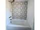 Charming tub with new showerhead, faucet, and gray and white floral-patterned backsplash at 3465 Peacock Ln, Mulberry, FL 33860