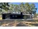 Striking modern house with a black exterior, large yard and mature trees at 3465 Peacock Ln, Mulberry, FL 33860