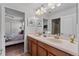 Bright bathroom features double sinks, wood cabinets, decorative art and an entry view to the bedroom at 1401 Wexford Way, Davenport, FL 33896