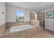Bright bathroom featuring a soaking tub with tile surround and a glass-enclosed shower at 1401 Wexford Way, Davenport, FL 33896