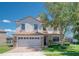 Charming two-story home with a stone-accented facade, tile roof, manicured lawn, and attached two-car garage at 1401 Wexford Way, Davenport, FL 33896