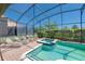 A screened-in pool and spa are surrounded by a brick patio and lush landscaping at 1401 Wexford Way, Davenport, FL 33896