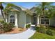 View of the front entry with green home, large windows and tropical landscaping in a residential area at 5446 Highlands Vista Cir, Lakeland, FL 33812