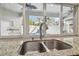 Bright kitchen sink featuring a double bowl, gooseneck faucet, and a large window with views of the outdoor pool at 5446 Highlands Vista Cir, Lakeland, FL 33812