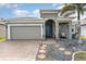 Home featuring a brick driveway, a two-car garage, and a charming entryway with a blue front door at 140 Trinity Ridge Cir, Davenport, FL 33897