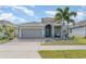 Charming single-story home features a well-manicured lawn, a brick driveway, and a cheerful blue front door at 140 Trinity Ridge Cir, Davenport, FL 33897