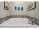 Close-up view of a bathtub with mosaic tile trim and modern fixtures at 25601 Hutcheson Ln, Sorrento, FL 32776