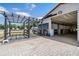 This barn features stalls, an overhang, and an adjoining black pergola, all set atop a light stone-look paver system at 25601 Hutcheson Ln, Sorrento, FL 32776
