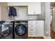 Functional laundry room with modern black washer and dryer, white cabinets, and ample counter space for convenience at 25601 Hutcheson Ln, Sorrento, FL 32776
