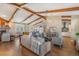 Spacious living room with exposed beams, hardwood floors, a stone fireplace, and lots of natural light at 25601 Hutcheson Ln, Sorrento, FL 32776