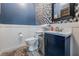 Chic half-bathroom featuring a blue vanity, patterned wallpaper, and white wainscoting, creating a stylish space at 25601 Hutcheson Ln, Sorrento, FL 32776