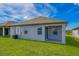 Backyard features a covered patio, green grass, and views of the adjacent pond at 3319 Chinotto Dr, Lake Alfred, FL 33850