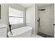 Elegant bathroom features a stylish tub and a tiled walk-in shower with black hardware at 133 Grovepark Dr, Davenport, FL 33837
