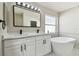 Well-lit bathroom with a dual sink vanity, a modern bathtub, and a large frameless mirror at 133 Grovepark Dr, Davenport, FL 33837
