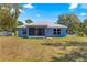 View of backyard featuring lawn with screened-in porch and mature landscaping at 12164 Se 85Th Ct, Belleview, FL 34420