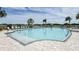 A clear swimming pool is lined with lounge chairs and lush landscaping, set against a backdrop of sunny skies at 2559 Driftwood St, Auburndale, FL 33823